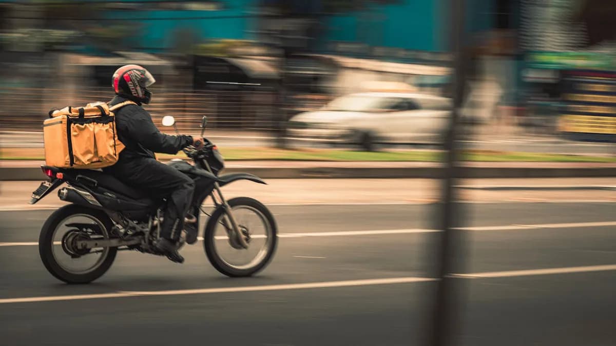 Repartidor conduciendo su motocicleta de trabajo en la ciudad